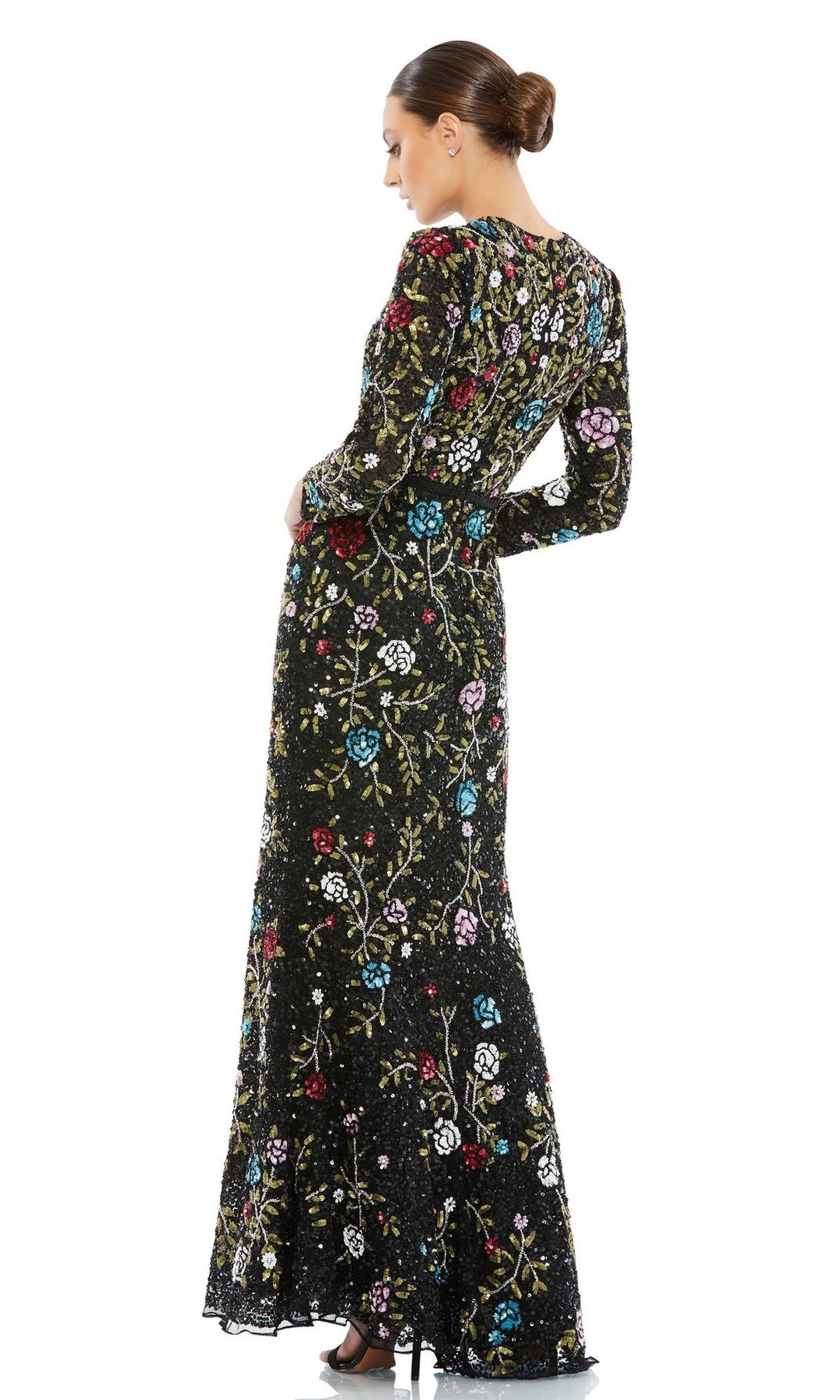 A woman with her hair in a bun, facing away, wears the Long Black Print Formal Dress: Mac Duggal 5556, featuring vibrant floral embroidery.